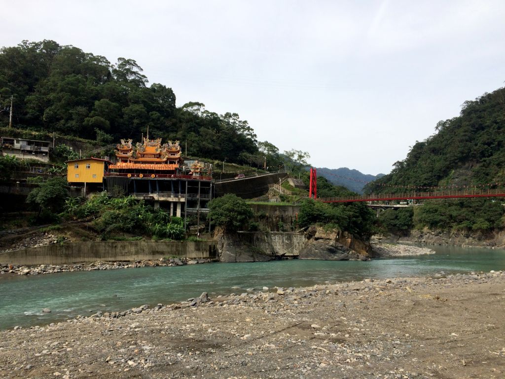 緑色の川とお寺と赤い吊橋